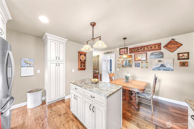 105 Shuksan St, Everson, WA 98247 - kitchen with freestanding refrigerator, light wood finished floors, white cabinets, decorative light fixtures, and light stone counters