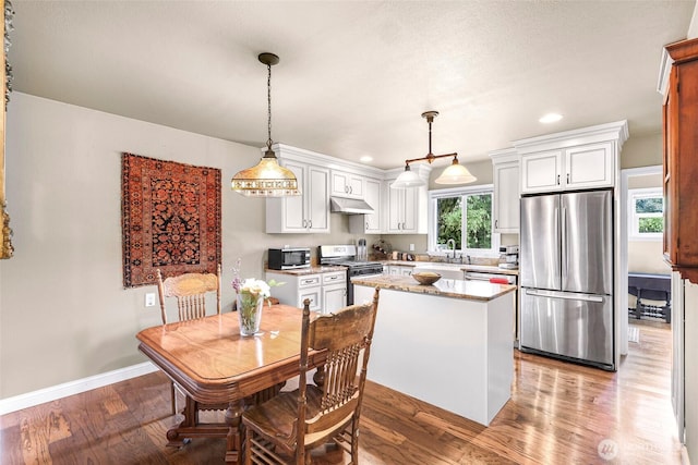 105 Shuksan St, Everson, WA 98247 - kitchen featuring appliances with stainless steel finishes, under cabinet range hood, a center island, white cabinets, and recessed lighting
