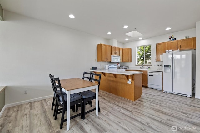 2311 Milton Way Unit E, Milton, WA 98354 - kitchen featuring white appliances, light wood finished floors, a peninsula, a skylight, and a kitchen bar