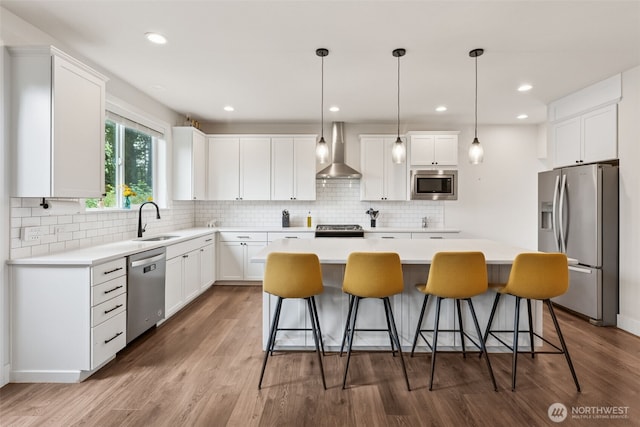 14717 73rd St E, Sumner, WA 98390 - kitchen with stainless steel appliances, wall chimney range hood, a center island, a kitchen bar, and wood finished floors