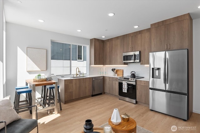 918 28th Ave S Unit A, Seattle, WA 98144 - kitchen featuring appliances with stainless steel finishes, light countertops, light wood finished floors, backsplash, and recessed lighting
