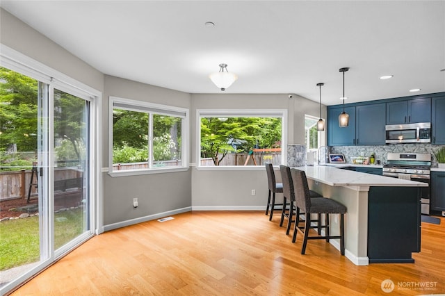 1818 Fisher Ave, Dupont, WA 98327 - kitchen with appliances with stainless steel finishes, light wood-style floors, a peninsula, a breakfast bar, and backsplash