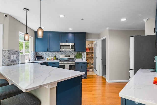 1818 Fisher Ave, Dupont, WA 98327 - kitchen featuring appliances with stainless steel finishes, a peninsula, blue cabinetry, light wood-style flooring, and a kitchen breakfast bar