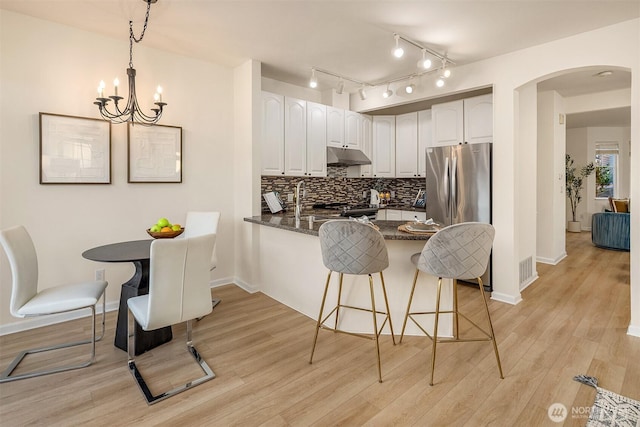 2840 139th Ave SE Unit 16, Bellevue, WA 98005 - kitchen featuring under cabinet range hood, a peninsula, freestanding refrigerator, arched walkways, and a chandelier