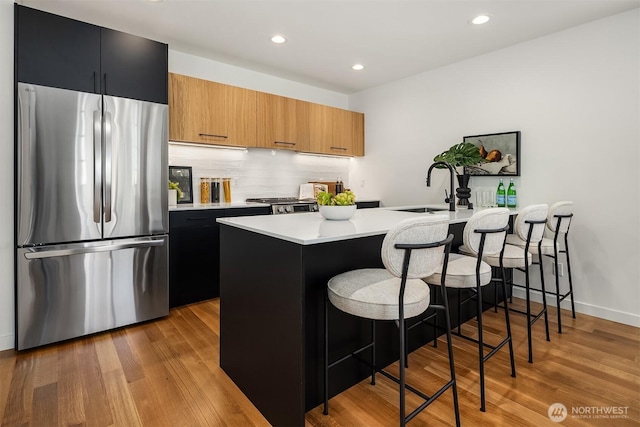 2419 NW 57th Unit B, Seattle, WA 98107 - kitchen featuring freestanding refrigerator, a breakfast bar, light countertops, tasteful backsplash, and wood finished floors