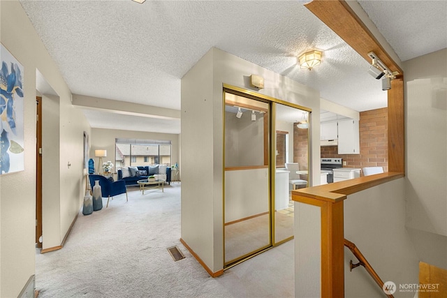 10637 Glen Acres Dr S Unit 10637, Seattle, WA 98168 - kitchen with white cabinetry, light colored carpet, a textured ceiling, stainless steel range with electric stovetop, and under cabinet range hood