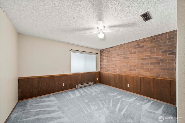 10637 Glen Acres Dr S Unit 10637, Seattle, WA 98168 - carpeted spare room with a baseboard heating unit, a ceiling fan, wooden walls, and a textured ceiling