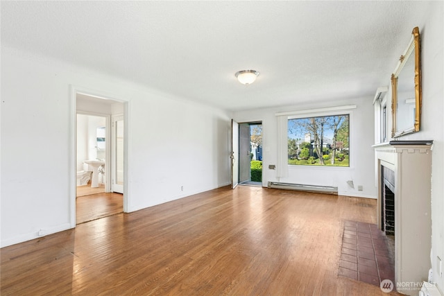 2000 31st Ave S, Seattle, WA 98144 - unfurnished living room featuring a fireplace with flush hearth, wood finished floors, and a baseboard heating unit