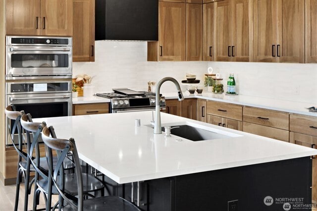 5412 Lonicera Dr, Blaine, WA 98230 - kitchen with stainless steel appliances, range hood, a breakfast bar area, and light countertops