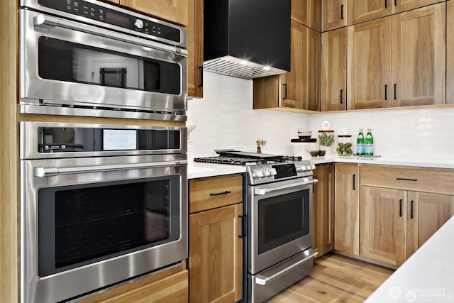 5412 Lonicera Dr, Blaine, WA 98230 - kitchen featuring stainless steel range with gas cooktop, wall chimney exhaust hood, light countertops, light wood finished floors, and decorative backsplash