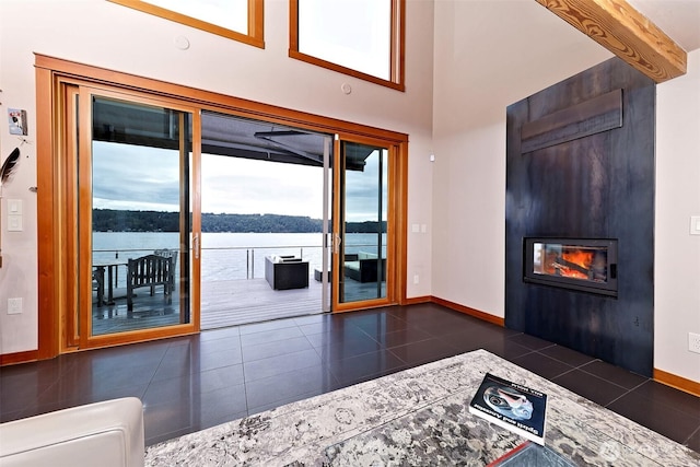 11261 E State Route 106, Union, WA 98592 - living area with a large fireplace, dark tile patterned floors, a water view, and a towering ceiling