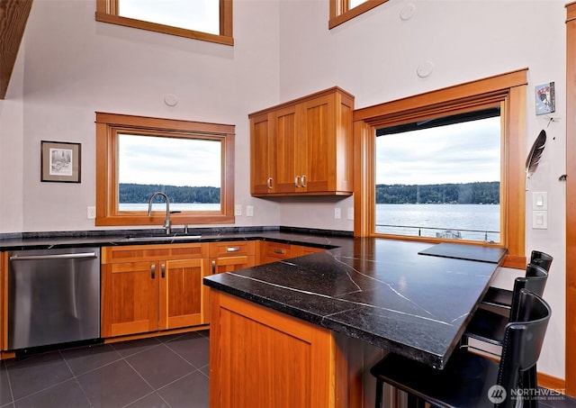 11261 E State Route 106, Union, WA 98592 - kitchen featuring stainless steel dishwasher, a kitchen breakfast bar, brown cabinetry, a peninsula, and a towering ceiling