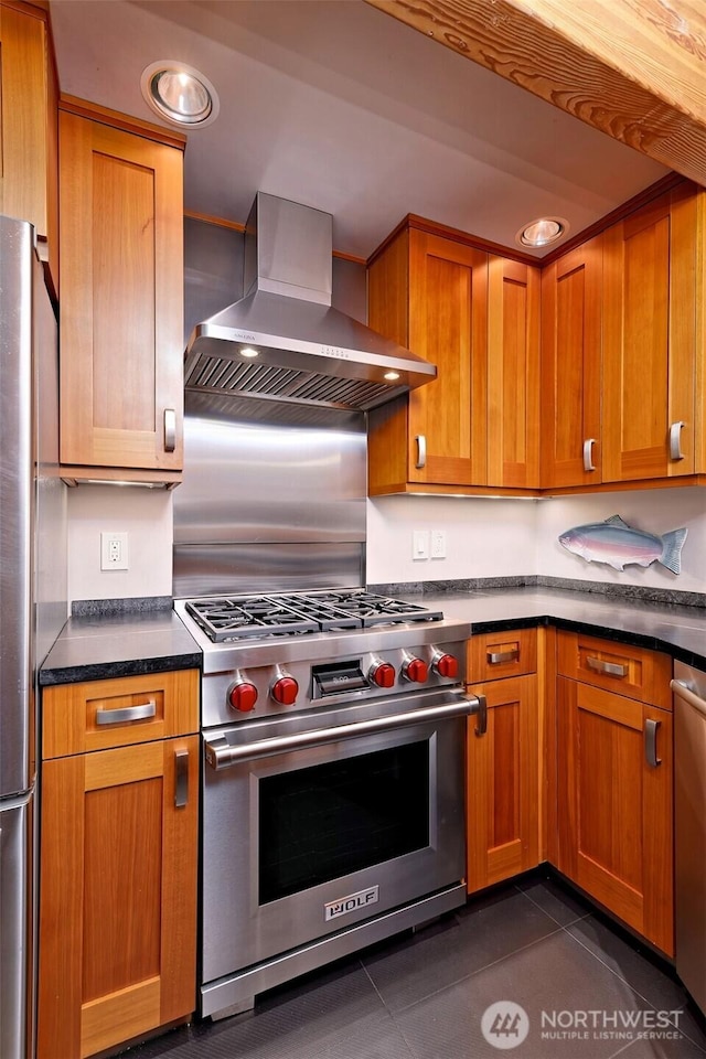11261 E State Route 106, Union, WA 98592 - kitchen with appliances with stainless steel finishes, wall chimney exhaust hood, dark countertops, brown cabinetry, and dark tile patterned floors