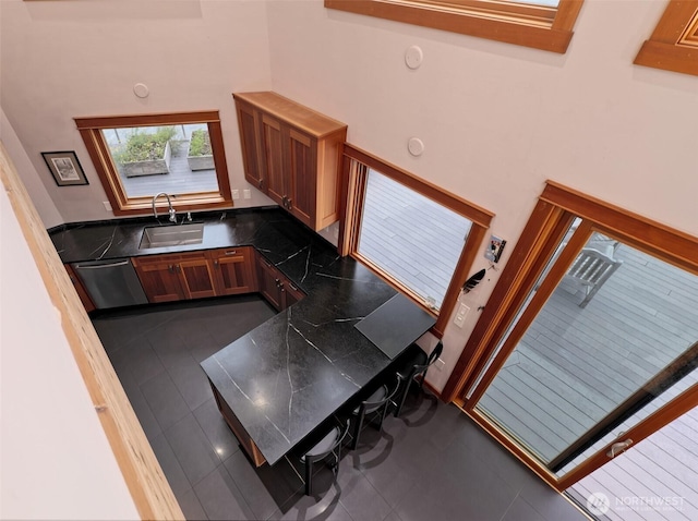 11261 E State Route 106, Union, WA 98592 - kitchen featuring dark countertops, stainless steel dishwasher, a high ceiling, dark tile patterned flooring, and brown cabinetry