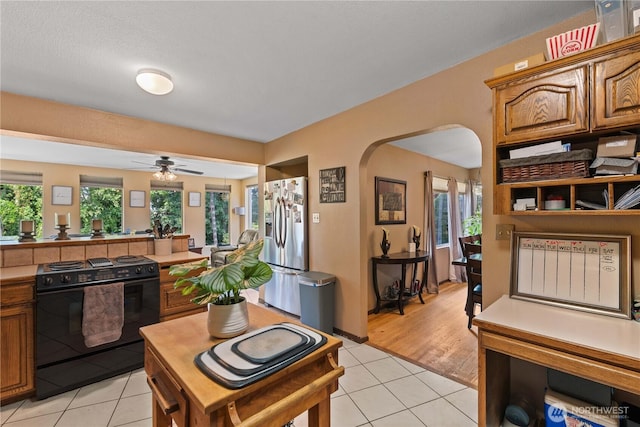 1714 N Astor Ct, East Wenatchee, WA 98802 - kitchen with black electric range oven, stainless steel fridge with ice dispenser, arched walkways, light tile patterned flooring, and a ceiling fan