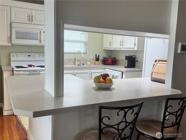3611 I St NE Unit 291, Auburn, WA 98002 - kitchen with white appliances, a breakfast bar area, white cabinetry, a peninsula, and light countertops
