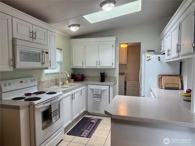 3611 I St NE Unit 291, Auburn, WA 98002 - kitchen with white appliances, vaulted ceiling, washer / clothes dryer, a skylight, and a peninsula