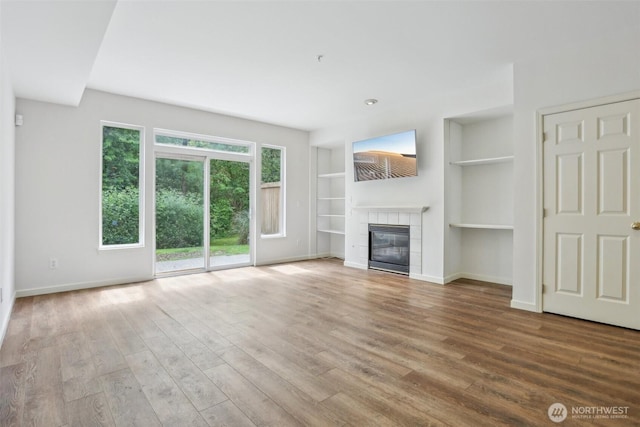 21616 9th Ave SE Unit C-105, Bothell, WA 98021 - unfurnished living room with wood finished floors, a tiled fireplace, and built in features