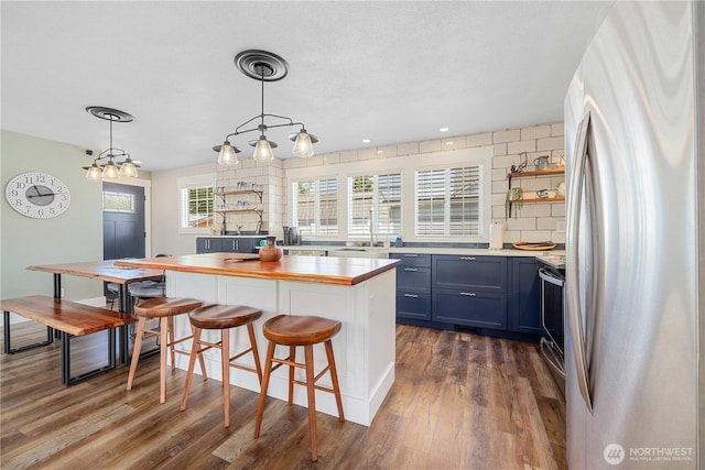 214 S Bradley St, Chelan, WA 98816 - kitchen with freestanding refrigerator, dark wood-style floors, electric range, blue cabinets, and a breakfast bar area