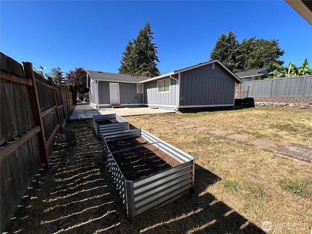 1221 E 63rd St, Tacoma, WA 98404 - rear view of house featuring board and batten siding, a vegetable garden, a fenced backyard, and a patio area