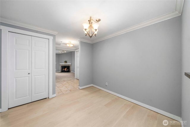 1839 S 286th Ln Unit S-201, Federal Way, WA 98003 - unfurnished dining area with ornamental molding, a chandelier, light wood-style floors, and a warm lit fireplace