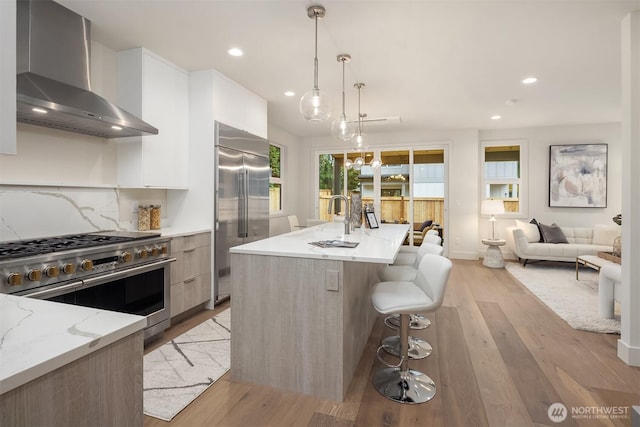 815 18th Ave W, Kirkland, WA 98033 - kitchen featuring wall chimney range hood, modern cabinets, high quality appliances, recessed lighting, and light wood-style floors