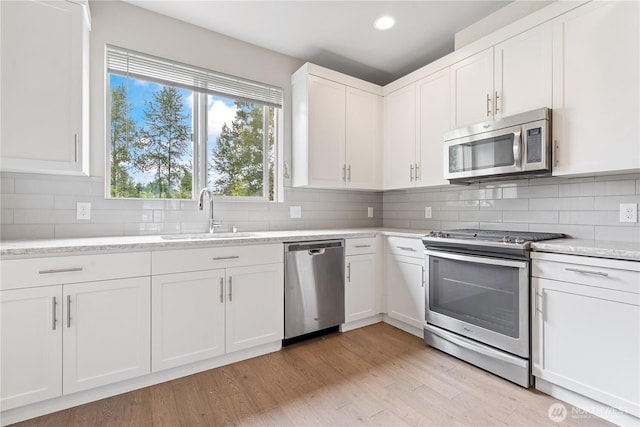 4239 NE 3rd Ln, Renton, WA 98059 - kitchen with stainless steel appliances, white cabinets, light wood finished floors, tasteful backsplash, and recessed lighting