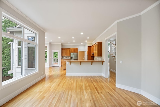 14691 NE 16th St, Bellevue, WA 98007 - kitchen with stainless steel fridge with ice dispenser, ornamental molding, healthy amount of natural light, light wood-style flooring, and a peninsula