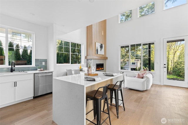 10520 NE 111th Pl, Kirkland, WA 98033 - kitchen with dishwasher, light wood-type flooring, a kitchen breakfast bar, light countertops, and a high ceiling