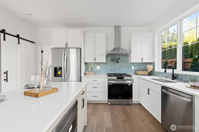 10520 NE 111th Pl, Kirkland, WA 98033 - kitchen featuring appliances with stainless steel finishes, wall chimney range hood, light countertops, a barn door, and wood finished floors