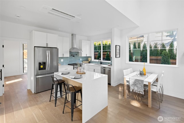 10520 NE 111th Pl, Kirkland, WA 98033 - kitchen with appliances with stainless steel finishes, wall chimney exhaust hood, a breakfast bar, and light wood finished floors