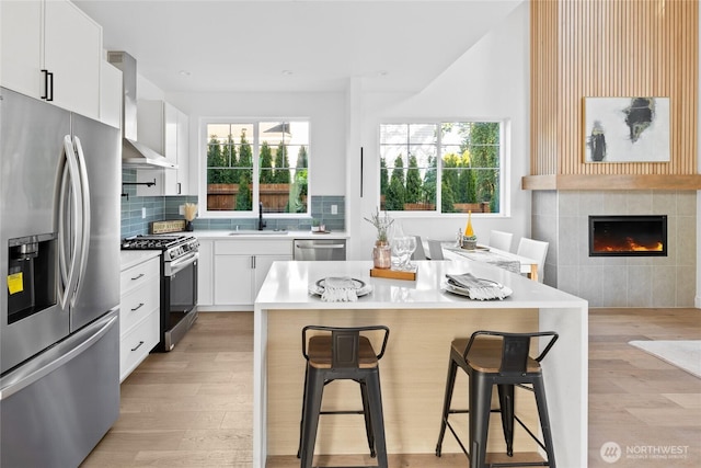 10520 NE 111th Pl, Kirkland, WA 98033 - kitchen featuring appliances with stainless steel finishes, a breakfast bar area, wall chimney range hood, and light wood finished floors