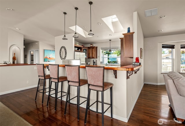 1223 Rainier Ln, Oak Harbor, WA 98277 - kitchen featuring stainless steel fridge, dark wood-style floors, a skylight, a kitchen bar, and hanging light fixtures