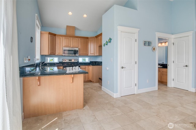 440 Marine View Dr SW Unit 3, Ocean Shores, WA 98569 - kitchen with stainless steel appliances, a breakfast bar area, a peninsula, high vaulted ceiling, and dark stone counters