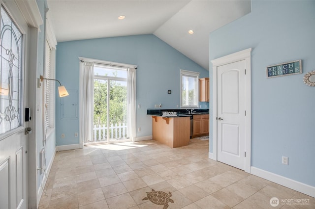 440 Marine View Dr SW Unit 3, Ocean Shores, WA 98569 - kitchen featuring vaulted ceiling, a breakfast bar, dark countertops, light tile patterned floors, and a peninsula