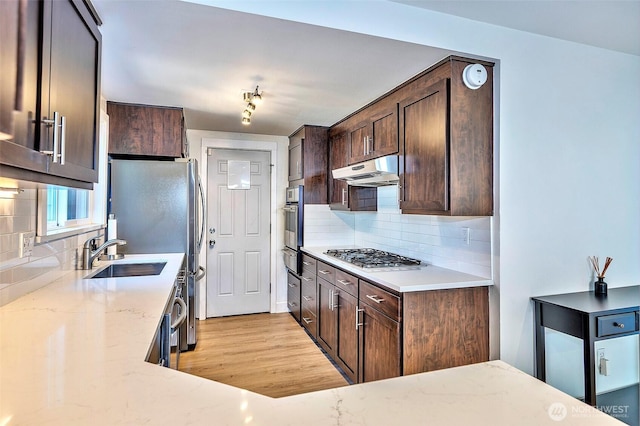 14305 109th Ave NE, Kirkland, WA 98034 - kitchen with stainless steel appliances, under cabinet range hood, dark brown cabinets, and tasteful backsplash