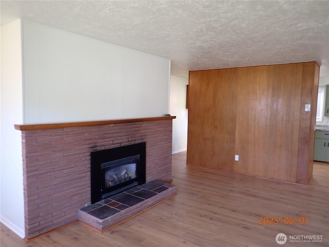 502504 4th St, Hoquiam, WA 98550 - unfurnished living room featuring wood finished floors, a textured ceiling, and a tile fireplace