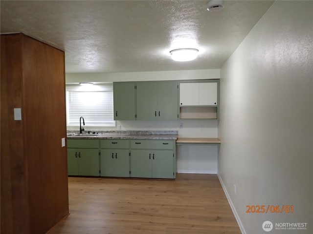 502504 4th St, Hoquiam, WA 98550 - kitchen featuring green cabinetry, light wood finished floors, a textured ceiling, and light countertops