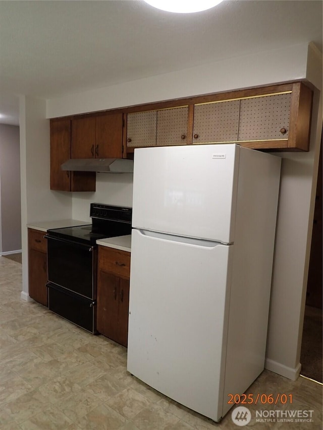 502504 4th St, Hoquiam, WA 98550 - kitchen with freestanding refrigerator, black / electric stove, under cabinet range hood, and light countertops