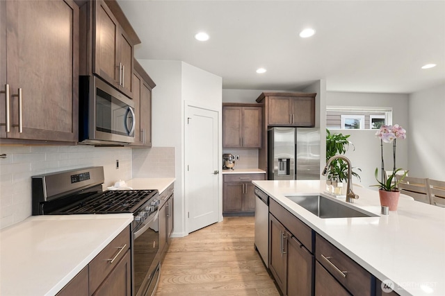 20821 98th Pl S, Kent, WA 98031 - kitchen featuring appliances with stainless steel finishes, light countertops, light wood finished floors, decorative backsplash, and recessed lighting