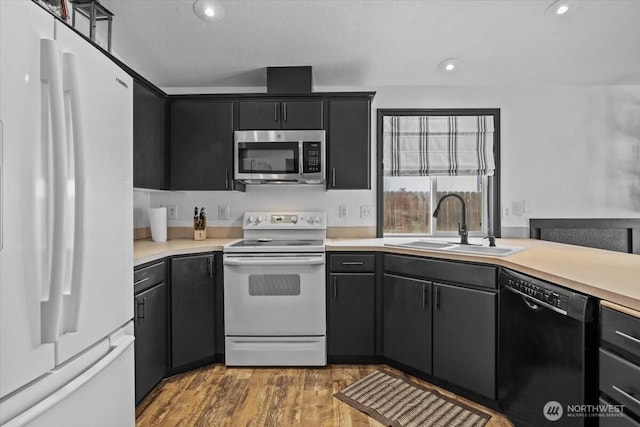 8308 Langara Dr, Pasco, WA 99301 - kitchen featuring white appliances, light countertops, dark cabinets, light wood finished floors, and recessed lighting