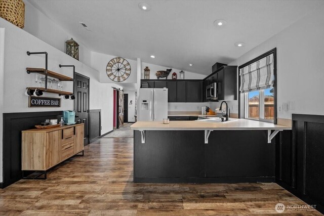 8308 Langara Dr, Pasco, WA 99301 - kitchen with white fridge with ice dispenser, lofted ceiling, light countertops, dark cabinets, and a peninsula