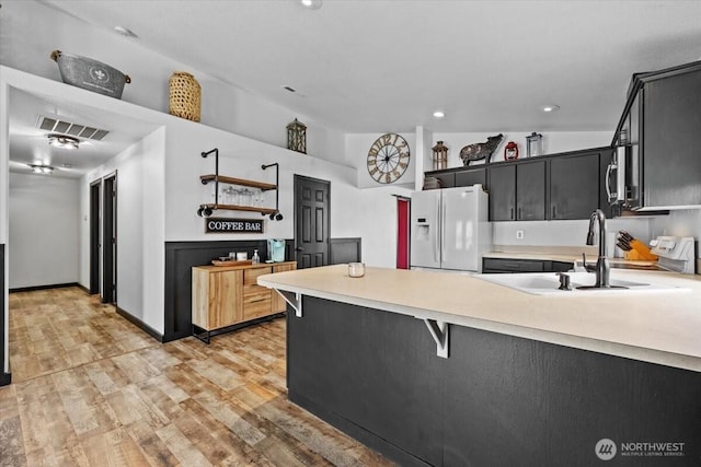 8308 Langara Dr, Pasco, WA 99301 - kitchen with white fridge with ice dispenser, a peninsula, light countertops, light wood-style flooring, and stainless steel microwave