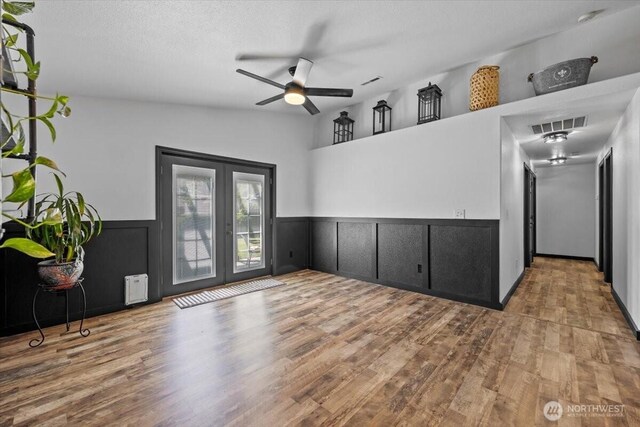 8308 Langara Dr, Pasco, WA 99301 - empty room with a ceiling fan, wood finished floors, a wainscoted wall, and french doors
