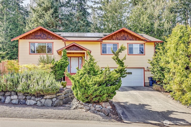 4243 Holcomb St, Port Townsend, WA 98368 - split foyer home with an attached garage, roof mounted solar panels, driveway, and roof with shingles