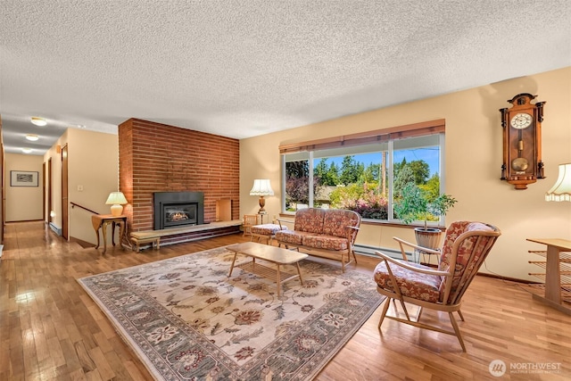 507 Lyla Ln, Bellingham, WA 98225 - living room with a textured ceiling, a brick fireplace, hardwood / wood-style floors, and baseboard heating
