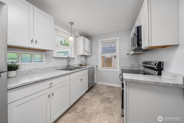 10812 2nd Ave S, Seattle, WA 98168 - kitchen with appliances with stainless steel finishes, white cabinetry, light countertops, decorative light fixtures, and stone finish flooring