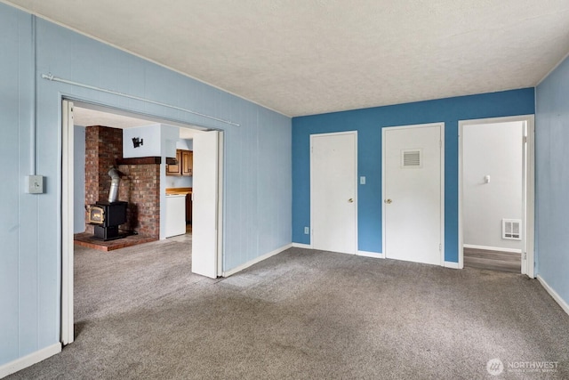 8597 Harborview Rd, Blaine, WA 98230 - unfurnished living room with a wood stove, carpet flooring, and a textured ceiling