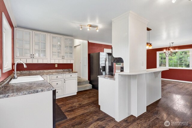 8597 Harborview Rd, Blaine, WA 98230 - kitchen featuring a peninsula, glass insert cabinets, dark wood-style flooring, white cabinets, and a chandelier