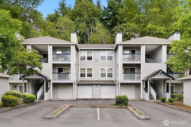 33020 10th Ave SW Unit 301, Federal Way, WA 98023 - view of building exterior featuring stairway, a garage, driveway, and view of scattered trees
